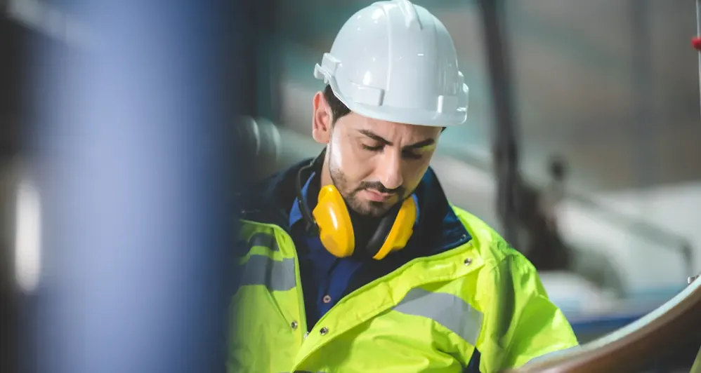 Operador de capacete concentrado em equipamento de fábrica